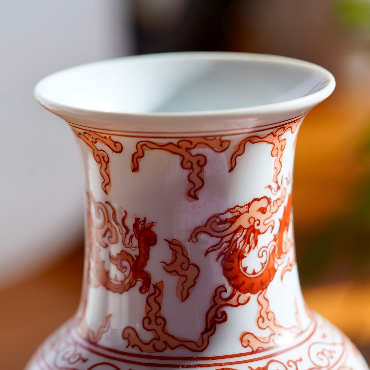 Macro photo of stem and rim of opening on vintage orange and white hand painted Japanese porcelain vase with dragons